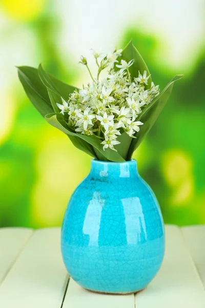 Beautiful mountain daffodils in color vase, on wooden table on bright background — Stock Photo, Image