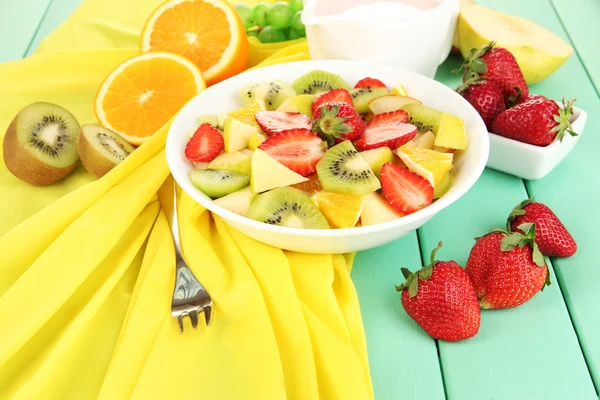 Useful fruit salad of fresh fruits and berries in bowl on napkin on wooden table close-up — Stock Photo, Image