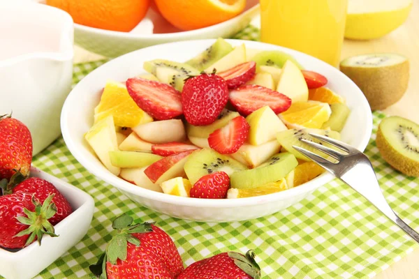 La ensalada útil de frutas frescas y las bayas en la escudilla a la servilleta a la mesa de madera el primer plano — Foto de Stock