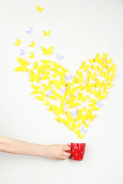 Paperi keltainen perhonen muodossa sydän lentää ulos kuppi — kuvapankkivalokuva