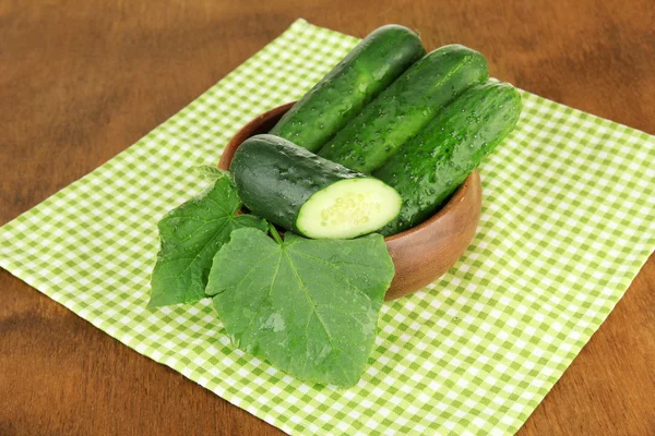 Schmackhafte grüne Gurken auf farbiger Serviette, auf Holzgrund — Stockfoto