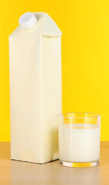 पीले पृष्ठभूमि पर टेबल पर दूध पैक — स्टॉक फ़ोटो, इमेज