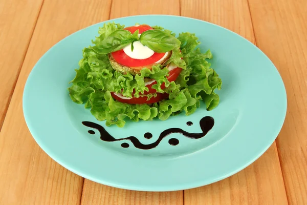 Sabroso tueste de médula y rodajas de tomate con hojas de ensalada, sobre fondo de madera —  Fotos de Stock