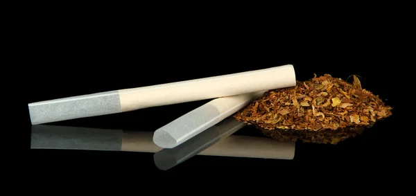 Табак и пустые сигаретные трубки, изолированные на черном — стоковое фото