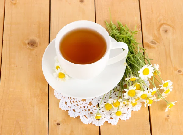 Чашка ромашкового чая и ромашки на деревянном столе — стоковое фото