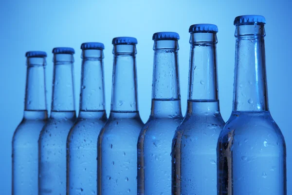 Vizes palackok kék háttér — Stock Fotó