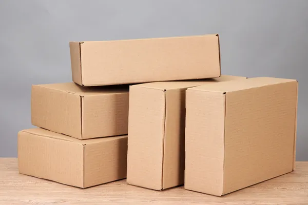 Cajas de paquetes sobre mesa de madera, sobre fondo gris —  Fotos de Stock