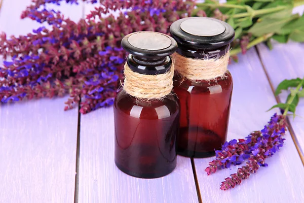 Garrafas de medicina e flores de salvia em fundo de madeira roxa — Fotografia de Stock