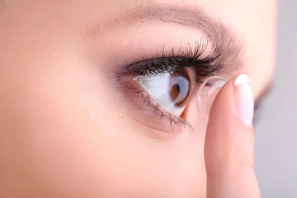 Jonge vrouw zetten contactlens in haar oog close-up — Stockfoto