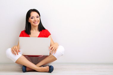 Odada dizüstü bilgisayar ile oturup güzel bir genç kadın
