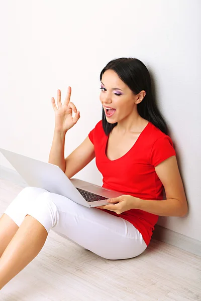 Mooie jonge vrouw zitten met laptop in de kamer — Stockfoto