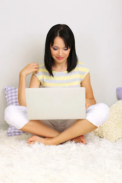 Bella giovane donna seduta con notebook in camera — Foto Stock