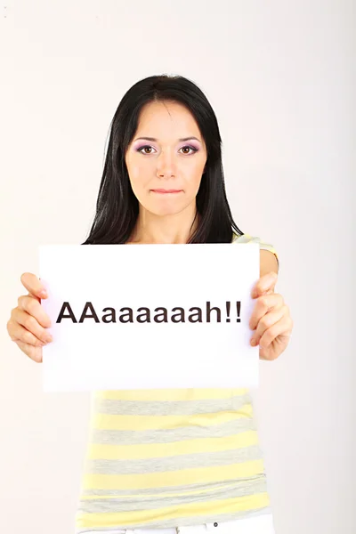 Здивована молода жінка тримає на сірому фоні напис "а" — стокове фото