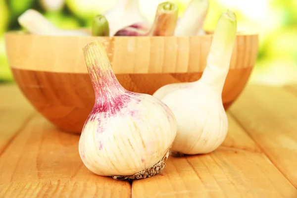 Frischer Knoblauch in Schüssel, auf Holztisch, auf hellem Hintergrund — Stockfoto