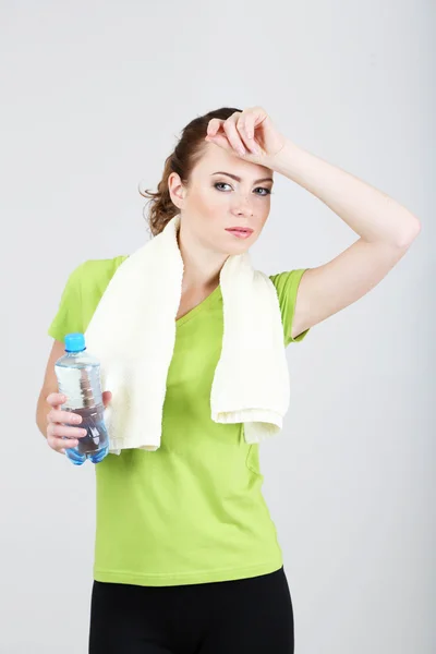 Beautiful young woman with bottle of water and towel — Stock Photo, Image