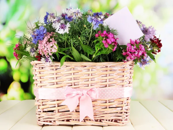 Bellissimo bouquet in cesto su tavolo in legno su sfondo naturale — Foto Stock