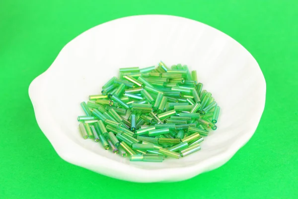 Cuentas verdes en el plato sobre fondo verde — Foto de Stock