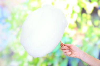 Pamuk şeker, sopayla parlak arka planda tutan el