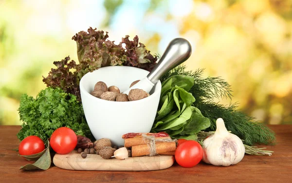 Komposition aus Mörser, Gewürzen, Tomaten und grünen Kräutern, auf hellem Hintergrund — Stockfoto