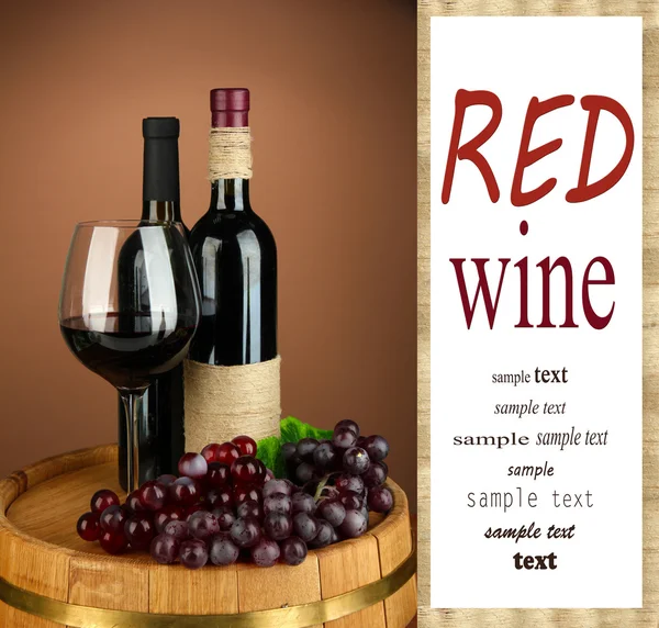 Composition of wine bottles, glass of red wine, grape on wooden barrel, on color background — Stock Photo, Image