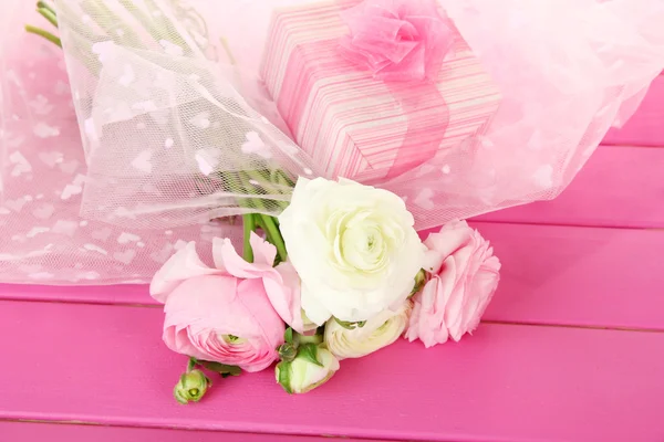 Ranunculus (Perzisch boterbloemen) en gift, op roze houten achtergrond — Stockfoto