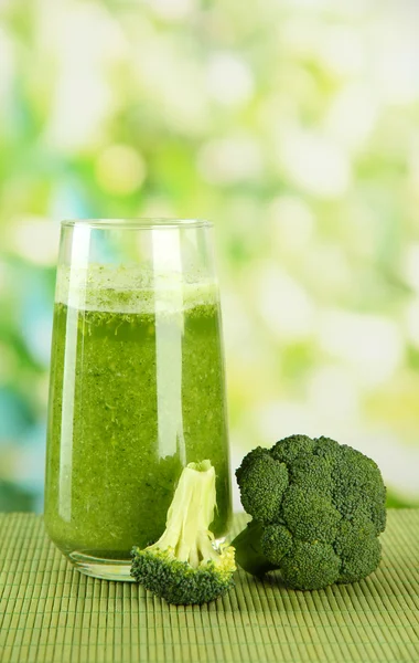Vaso de jugo de brócoli, sobre estera de bambú, sobre fondo verde — Foto de Stock