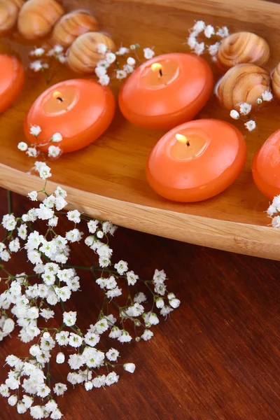 Красивые свечи в воде на деревянном столе крупным планом — стоковое фото