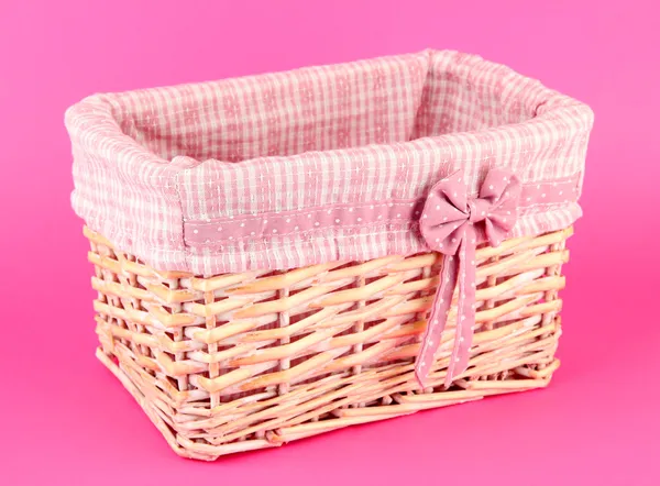 Wicket basket with pink fabric and bow, on color background — Stock Photo, Image