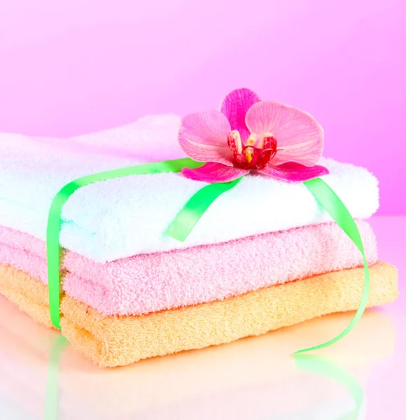 Towels tied with ribbon on light pink background — Stock Photo, Image