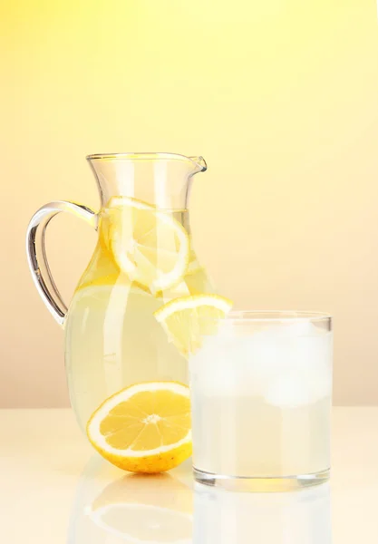 Лимонад в кувшине и стекле на желтом фоне — стоковое фото