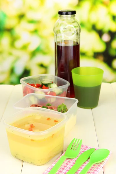 Leckeres Mittagessen in Kunststoffbehältern, auf Holztisch vor hellem Hintergrund — Stockfoto