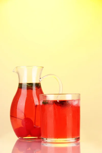 Kirschgetränk in Krug und Glas auf gelbem Hintergrund — Stockfoto