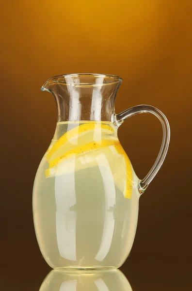 Lemonade in pitcher on orange background — Stock Photo, Image