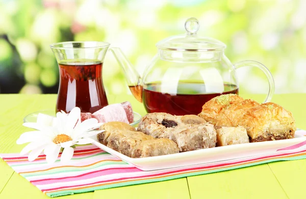 Baklava dulce en el plato con té en la mesa sobre fondo brillante — Foto de Stock