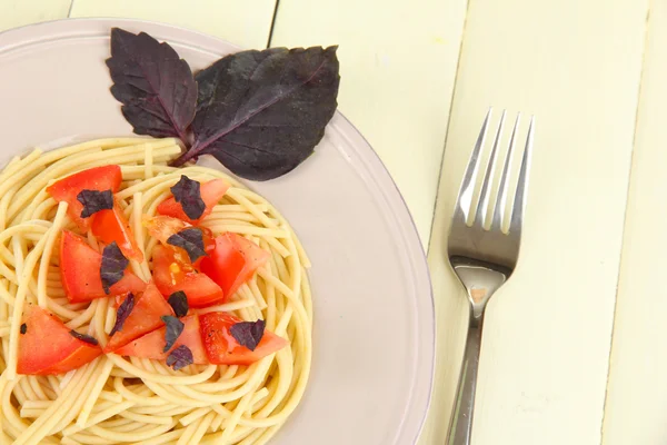 Spaghettis aux tomates et feuilles de basilic sur fond de bois — Photo