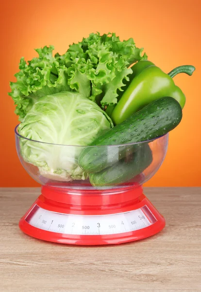 Verse groenten in schalen op tafel op oranje achtergrond — Stockfoto