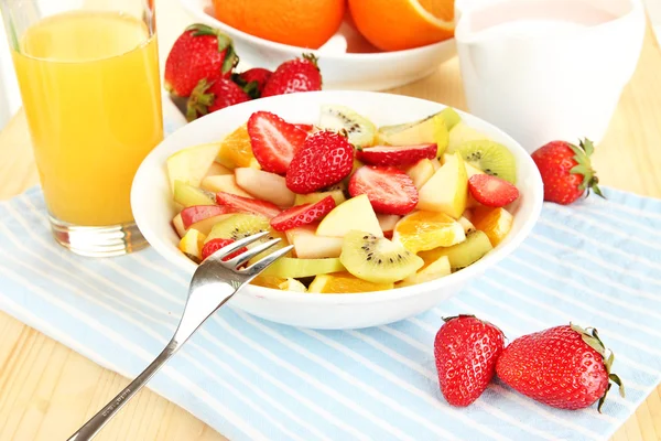 Useful fruit salad of fresh fruits and berries in bowl on napkin on wooden table close-up — Stock Photo, Image