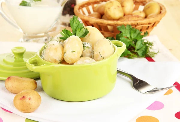 Tender young potatoes with sour cream and herbs in pan on wooden table close-up — Stock Photo, Image