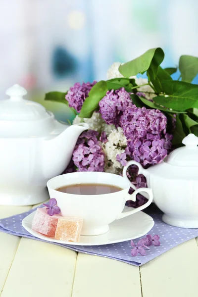 Composición con hermosas flores lila, servicio de té sobre mesa de madera sobre fondo brillante —  Fotos de Stock