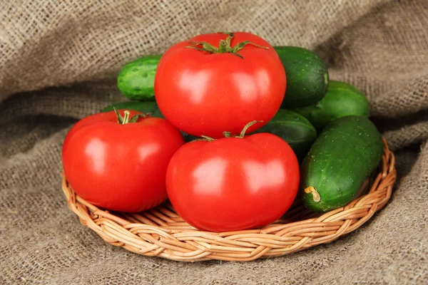 Pepinos verdes saborosos e tomates vermelhos no fundo de pano de saco — Fotografia de Stock