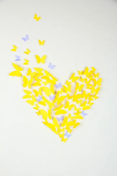 Paper yellow butterfly in form of heart on wall — Stock Photo, Image