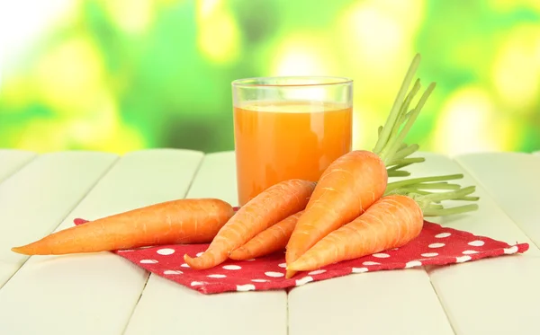 Heap of carrots and green apple, glass of juice, on color wooden table on bright background — Stock Photo, Image