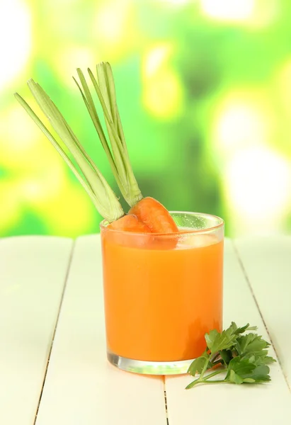 Vidro de suco de cenoura, na mesa de madeira a cores no fundo brilhante — Fotografia de Stock