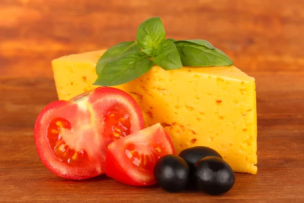 Сыр, базилик и овощи на деревянном фоне — стоковое фото