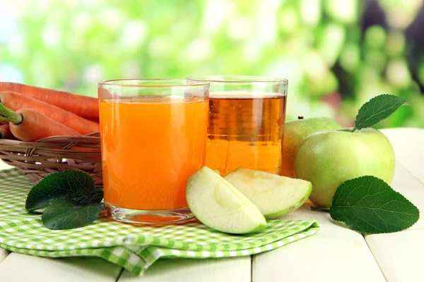 緑色の背景で白の木製のテーブルの上にニンジン、リンゴ ジュースのグラス — ストック写真