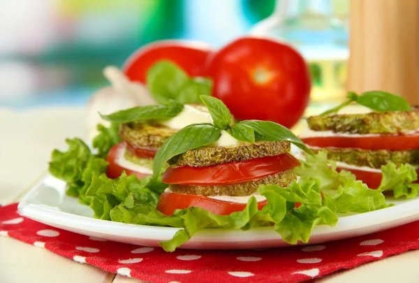 Tasty roasted marrow and tomato slices with salad leaves, on bright background — Stock Photo, Image