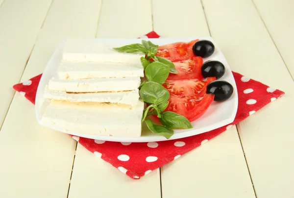 Schapen melk kaas, met basilicum en tomaat op kleur servet op houten achtergrond — Stockfoto