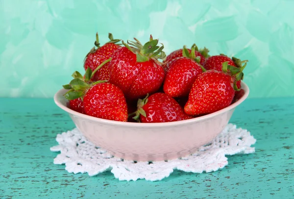 Erdbeeren im Teller auf Serviette auf blauem Hintergrund — Stockfoto