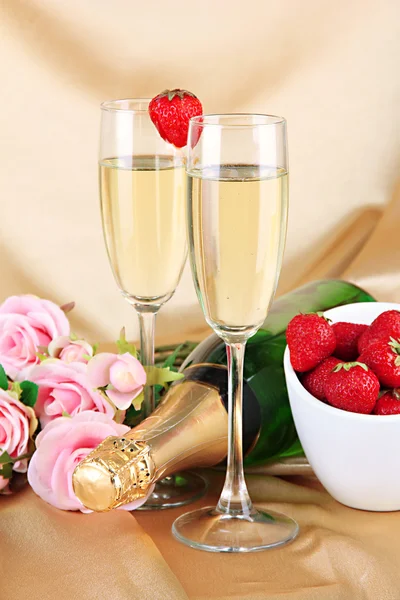 Bodegón romántico con champán, fresa y rosas rosadas, sobre fondo de tela de color —  Fotos de Stock