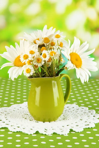 Beautiful bouquet chamomiles in pitcher on tablecloth on natural background — Stock Photo, Image